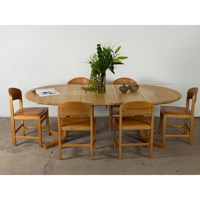 Round dining table in ash from the 1970s, designed with two extension leaves that transform the circular top into a...