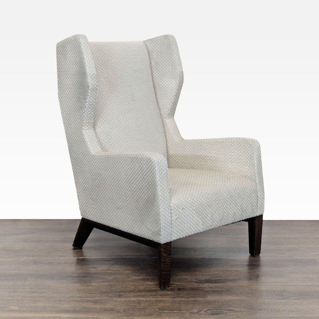This Holly Hunt lounge chair features a stylish wingback design and is upholstered in a soft, textured cream fabric. Its...