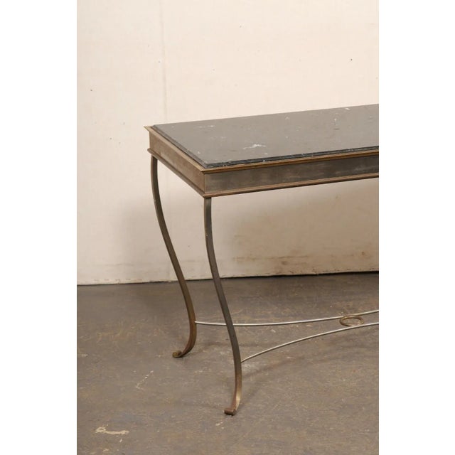 A mid-century metal frame console table with black marble top. This vintage table, circa 1960's, features a rectangular-...