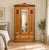 An Edwardian ash wardrobe with Arts and Crafts influence, featuring a decorative carved crest, floral carved panels, a...