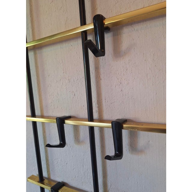 Mid century large wall mounted coat and hat rack in brass, brass-overlay and metal with 12 plastic shaped hooks that can...