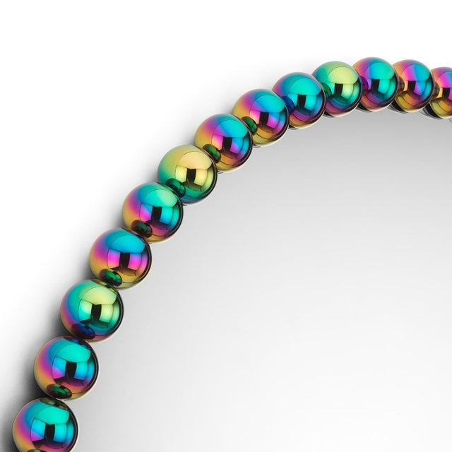 The Gioiello mirror features a frame composed of polished, multicolored brass spheres arranged in a continuous loop. This...