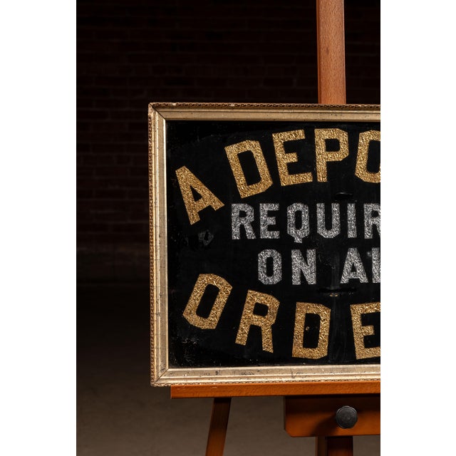 Reverse on glass (ROG) trade sign featuring gold and silver foil lettering against a black ground, reading "A DEPOSIT...