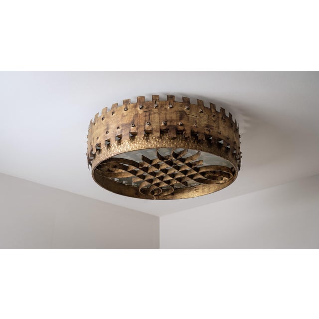 This ceiling lamp reflects the Brutalist movement of the mid-century, 1940s, with a wrought iron frame finished in a warm...