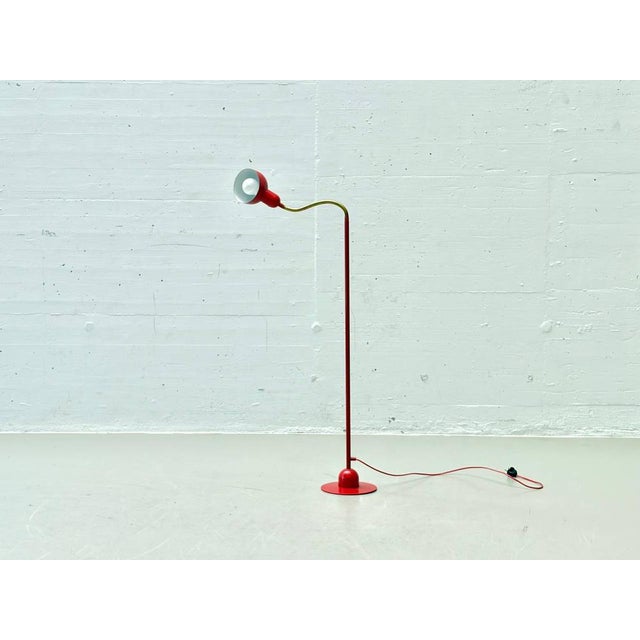 A sleek, functional floor lamp in vibrant red lacquered metal, instantly eye-catching with its clean lines and flexible...