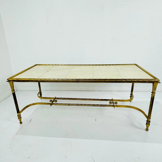 Elegant French cocktail table featuring a solid cast brass frame with a large parchment + wood tabletop. The brass is...