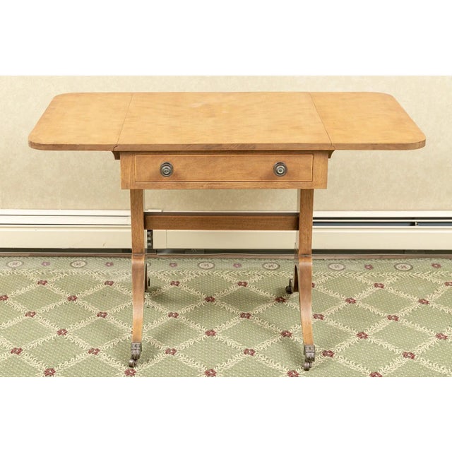 Regency style drop leaf side accent table on casters with two drawers, straight stretcher, brass pulls and toe caps....