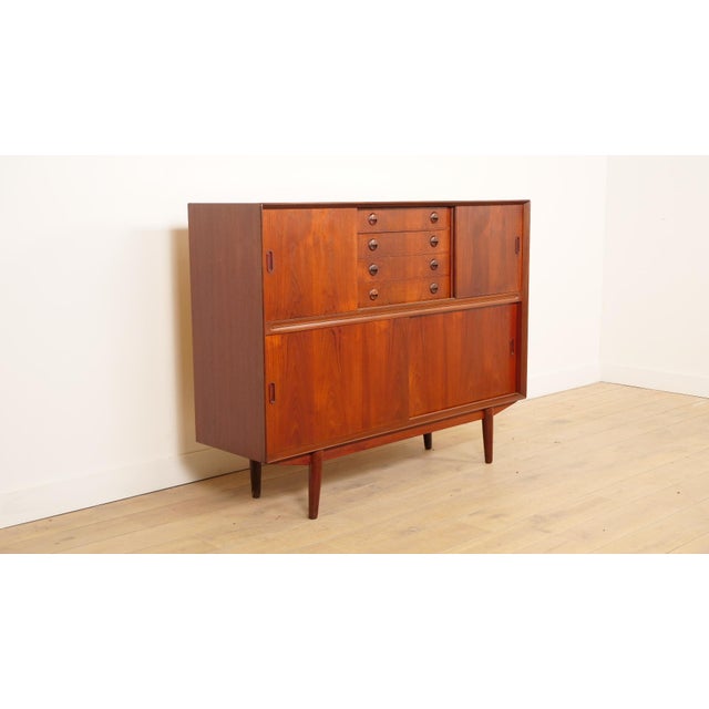 A beautiful vintage highboard in warm teak, featuring characteristic 1960s Danish design. This Danish cabinet boasts clean...