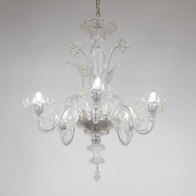 This handcrafted Cristallo Murano chandelier has five undulating scroll arms and features a bulbous center column with...