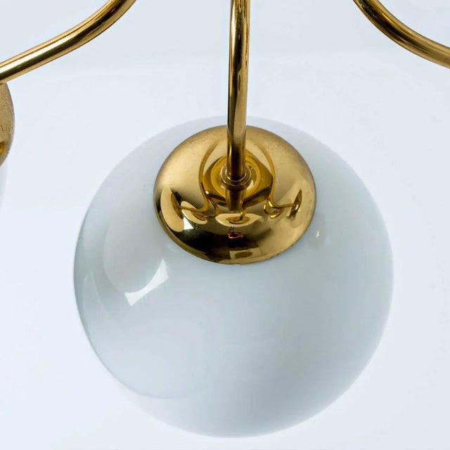 A wonderful round brass chandelier, circa 1970, made by glashütte limburg, germany. With hand-blown white glass on a brass...