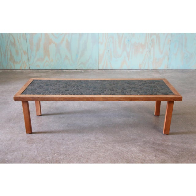A large rectangular coffee table with a mix of gray coin tiles made by Jane and Gordon Martz in the 1960s for Marshall...