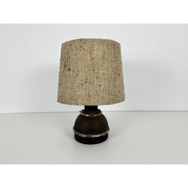 A beautiful large table lamp made in the 1960s. The base is made of brown ceramic. The lamp shade has a beige color. The...