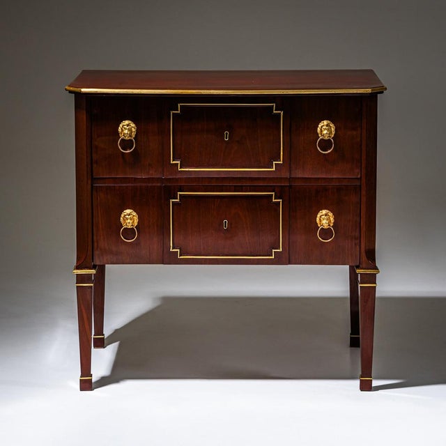 Neoclassical chest of drawers with two drawers, raised on block-mounted tapered square legs. The piece is veneered in...