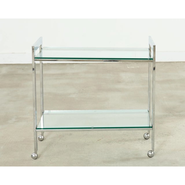 Stylish mid-century modern chrome and glass two tier bar cart made in the style and manner of Milo Baughman. The cart is...