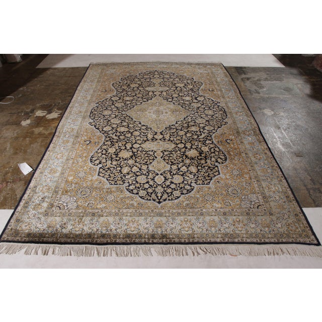 A 7x11 vintage Qum rug in a regal medallion style, enjoying hues of beige-brown atop black with comfortable blue accents....
