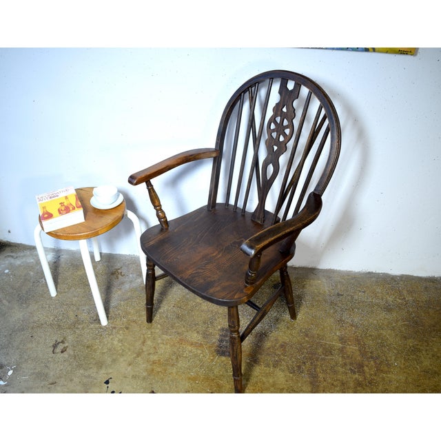 This is an antique Windsor wheelback chair from England. The chair has turned legs and a carved central spindle. This...