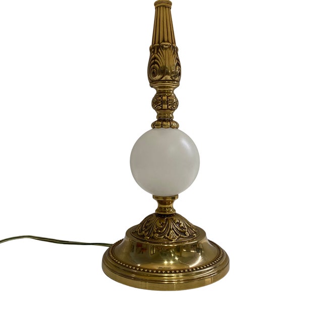 Elegant vintage table lamp featuring a substantial solid brass construction paired with a frosted white glass orb accent....