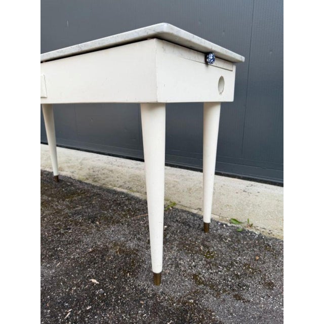 White lacquered wood kitchen table with a white marble top with gray veining. The table is rectangular, with a large...
