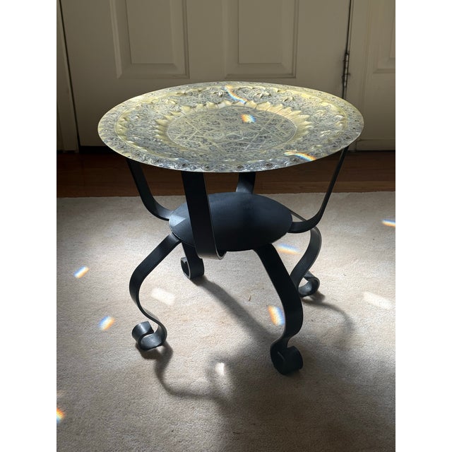 This round table features a removable brass tray top intricately hand-engraved with geometric and floral motifs, resting...
