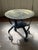 This round table features a removable brass tray top intricately hand-engraved with geometric and floral motifs, resting...