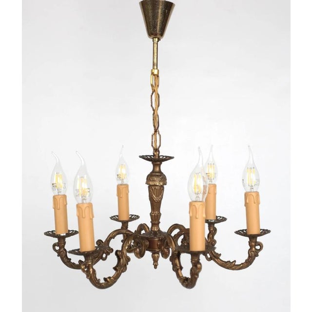 Antique chandelier made of patinated brass in the rococo style. Rarer model with cut-out bowls. The chandelier has...