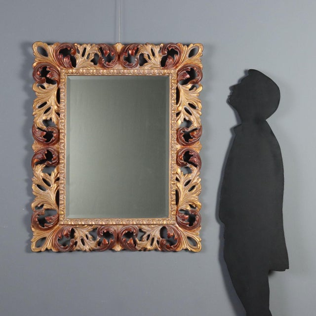 Baroque style mirror crafted from finely carved and gilded wood, dating back to mid-20th century Italy. The frame features...