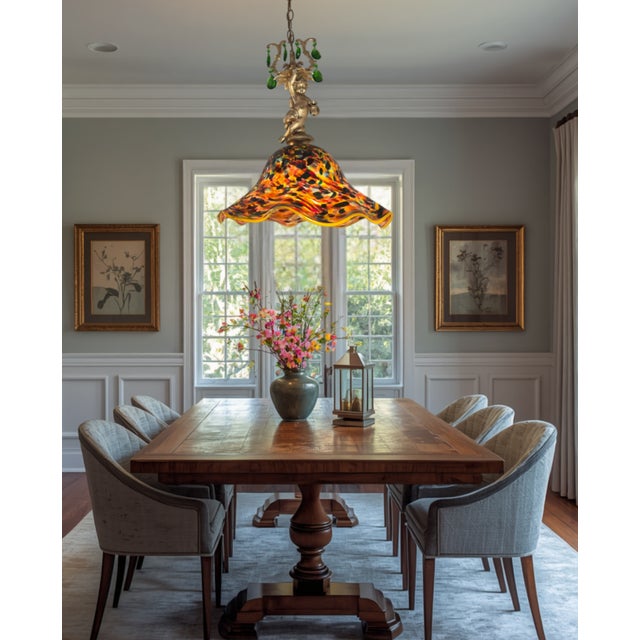This one‑of‑a‑kind pendant light combines a contemporary handblown art‑glass shade with vintage brass tone components. The...
