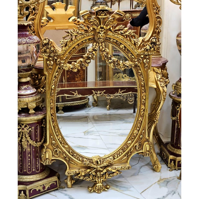 Make a grand statement with this extraordinary oval wall mirror, featuring an elaborate sculpted frame finished in radiant...