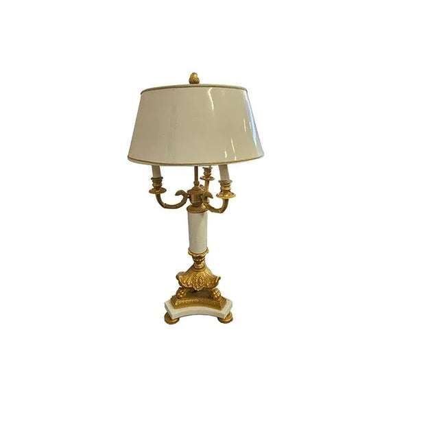 Three-light table lamp in bronze and white marble, body chiseled with Empire motifs, resting on a tripod base, minor...