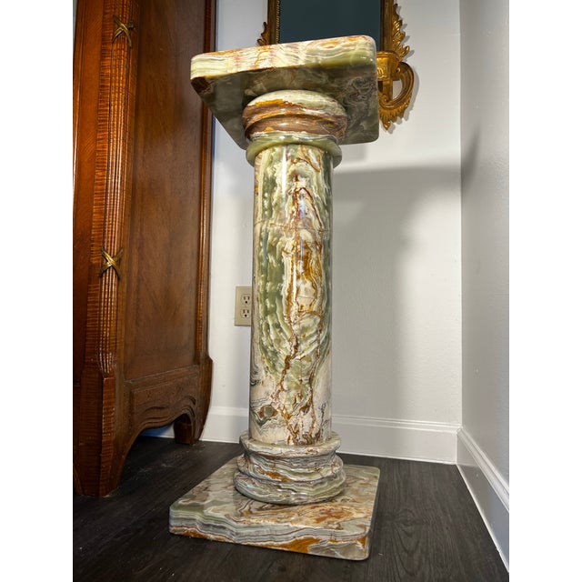 Elegant vintage pedestal crafted from solid green onyx, showcasing beautifully layered natural banding in shades of jade,...