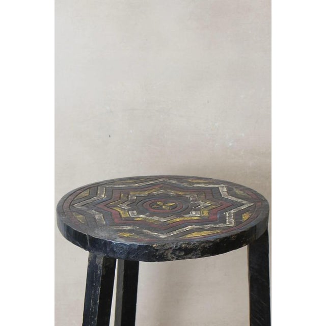 Vintage Ethiopian coffee table, characterized by its rustic wooden construction, two-tiered design, and a striking top...