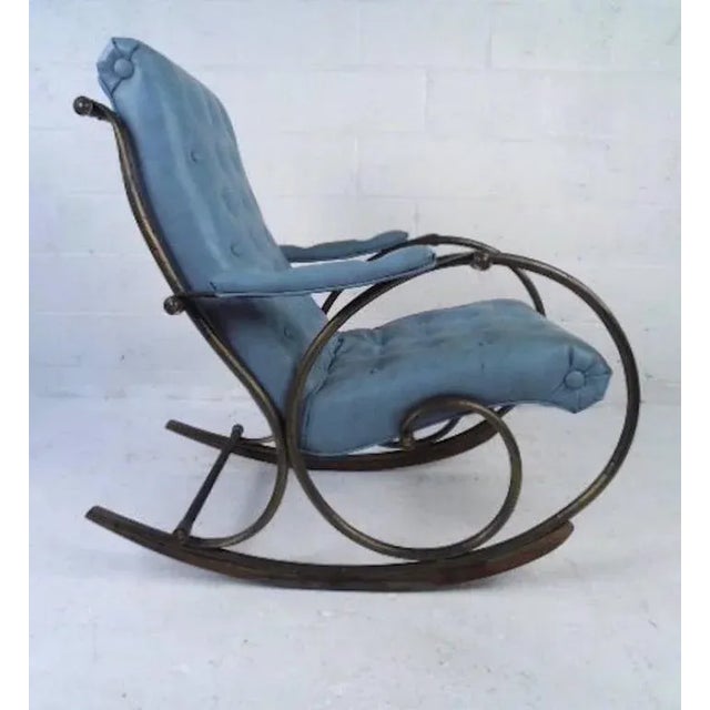 This sculpted metal frame rocking chair with tufted vinyl upholstery makes a stylish and comfortable addition to any...