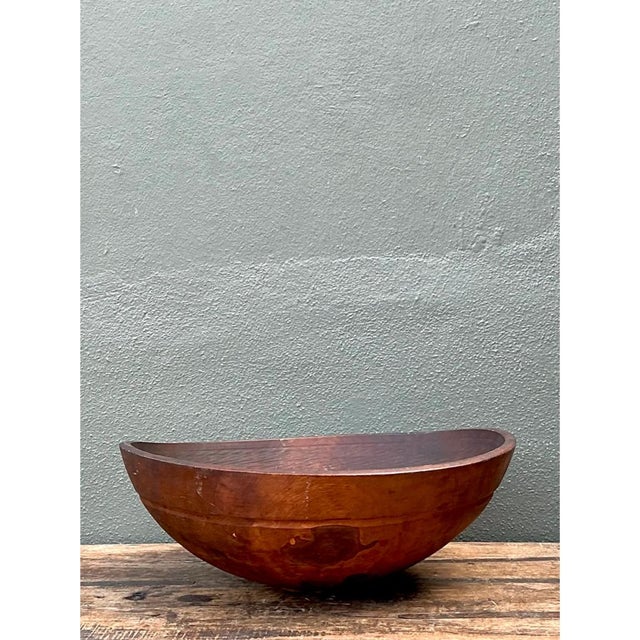 This vintage bowl is an oversized, hand-carved vessel with a broad, softly oval form that swells from a small, discreet...