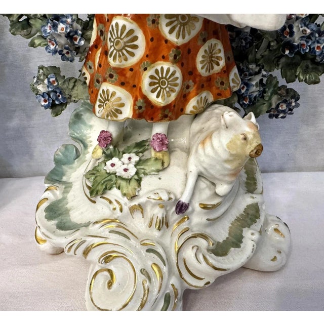 An incredible pair of English Chelsea Derby bocage figurines, circa 1760's. The male figure plays a flute, while a dog...