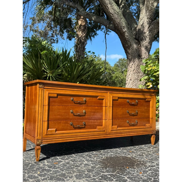 Elegant vintage Thomasville dresser featuring a beautifully crafted campaign-inspired design with clean architectural...