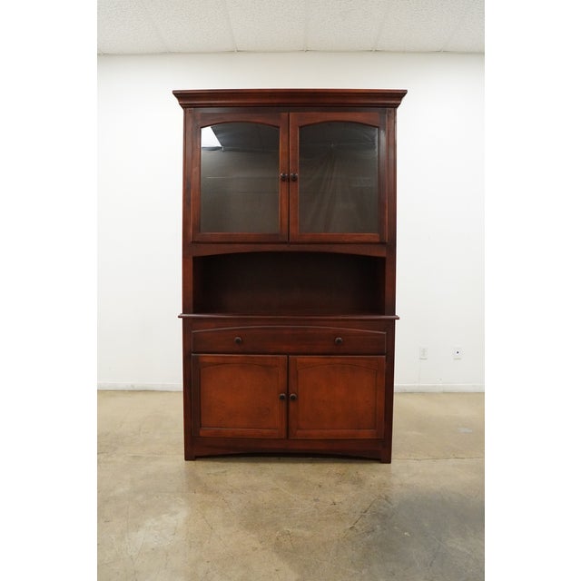 This Bassett Furniture china cabinet features a warm reddish-brown wood finish with clean traditional detailing and a...