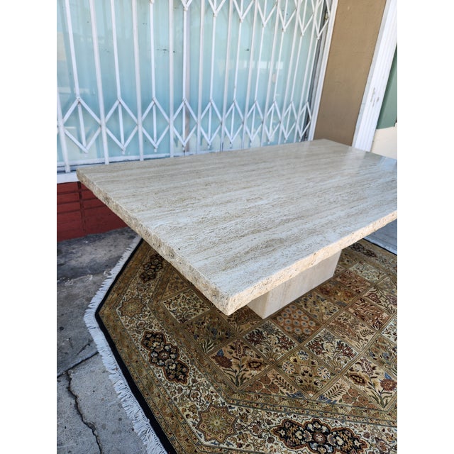 Elegant dining table is made of solid travertine stone. The piece has a natural beige and cream color palette with a...