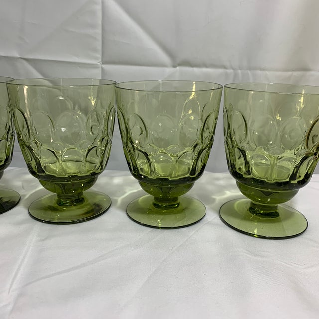 Offered here are mid-century Fostoria Mesa Olive Green footed juice/wine glasses, which feature a signature pressed...