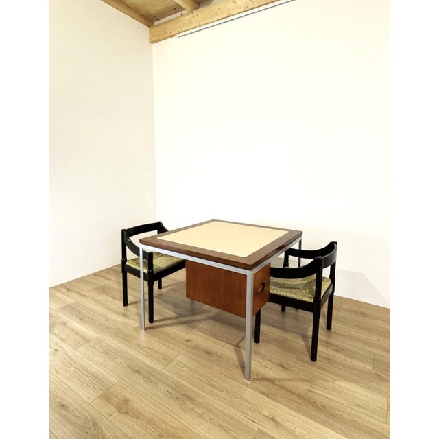 A unique double-desk centerpiece, featuring a metal frame and wooden elements, and a top covered in ivory-colored faux...