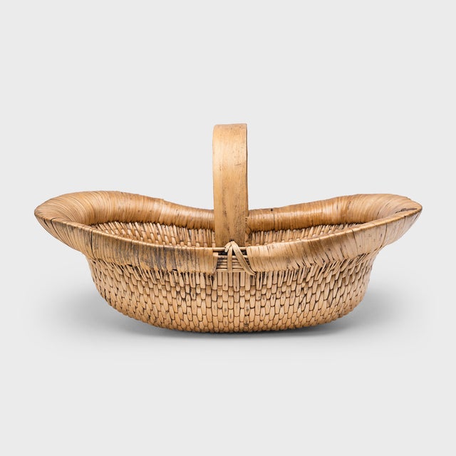 Expertly woven of reeds and fine cord, this large Chinese market basket has a wide, oblong shape with a shallow interior...