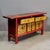 Authentic early 1900's Chinese sideboard featuring vibrant red framing with hand-painted yellow panels depicting...