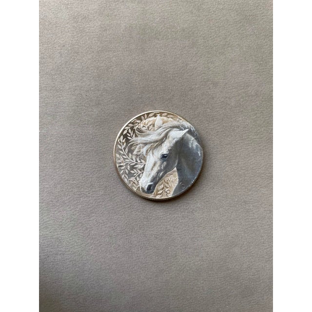 This intricate oil painting on an etched coin features the serene portrait of a horse, its flowing mane captured with...