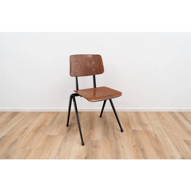 Model S17 by Galvanitas. The chair comes with a brown wooden seating and backpiece on a black metal frame. This piece has...