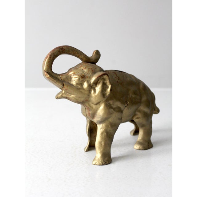 Antique cast iron elephant bank with a worn gilt finish. This whimsical piece features a classic elephant design, perfect...