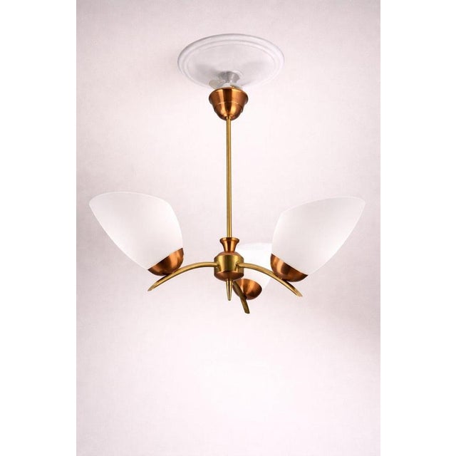 Elegant Swedish three-arm chandelier from the 1950s, executed in a refined combination of brass and copper with opaline...