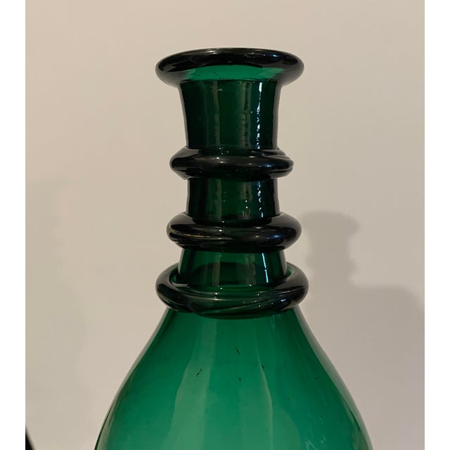 Antique green glass decanter, ovoid body with three ringed neck ending in a flared lip. Partially polished pontil on the...