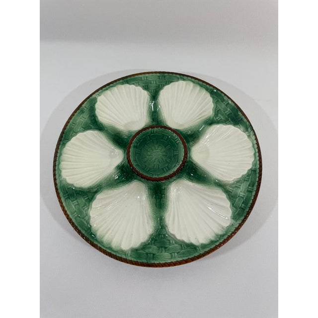 A striking antique French Faience Longchamp glazed majolica oyster plate with a vibrant green basket weave background and...