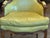 A bergère with a shaped back and upholstered in green leather, outlined with rows of nailhead trim that follow the curves...