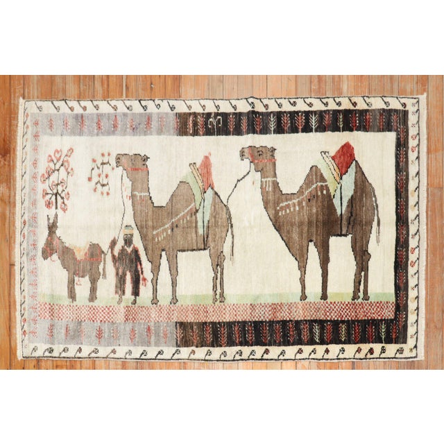 Mid 20th century colrufl Turkish rug depicting camel and donkeys on an ivory ground. The striation of colors on 1 end is...