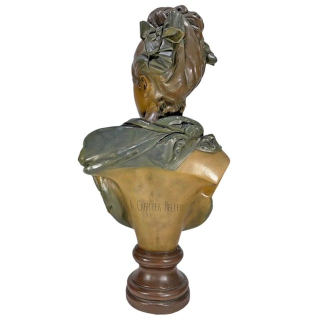 Decorative patinated plaster bust of an elegant young woman modeled with her hair arranged in an elaborate updo adorned...